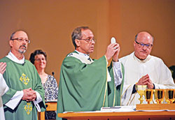 Archbishop Charles C. Thompson, center, elevates the Eucharist during an Oct. 10 Mass at SS. Peter and Paul Cathedral in Indianapolis. Deacon Robert Beyke, left, assists at the Mass. Msgr. William F. Stumpf, right, concelebrates. Jeanne Chandler, second from left, cantor at the Mass, looks on. (Photo by Natalie Hoefer)