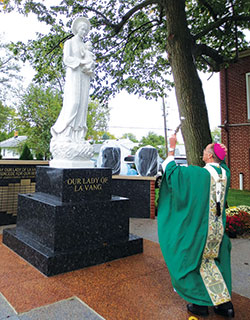 Archbishop Charles C. Thompson blesses a new statue of Our Lady of La Vang on Oct. 15 installed on the grounds of St. Joseph Parish by the archdiocesan Vietnamese Catholic Community. (Photo by Katie Rutter)