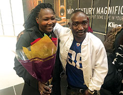 The joyous reunion of a parent and child shows as Bershlmaws “Alo” Koko greets his mother, Nasra Anglo, with a bouquet of red roses on Oct. 19 at Indianapolis International Airport. Alo, a refugee of Sudan who came to the United States in January, was reunited with nine members of his family on that October evening. (Submitted photo)