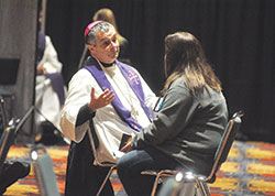 Bishop William F. Medley of Owensboro, Ky., speaks on Nov. 17 with a National Catholic Youth Conference participant during the sacrament of penance celebrated in a large conference room in the Indiana Convention Center in Indianapolis. Dozens of priests and bishops heard confession for hours during the conference. (Photo by Sean Gallagher)
