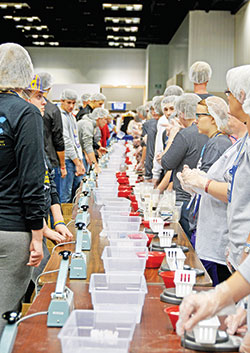 In the Indiana Convention Center in Indianapolis during the National Catholic Youth Conference, volunteers prepare to make pre-packed meals on Nov. 18 to be sent to Burkina Faso as part of a conference-long service project to help Catholic Relief Services’ Helping Hands program. (Photo by Natalie Hoefer)