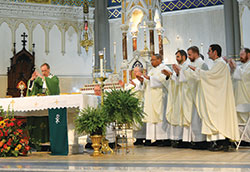 Archbishop Charles C. Thompson, left, prays the eucharistic prayer during a Mass for archdiocesan participants at the National Catholic Youth Conference at St. John the Evangelist Church on Nov. 16. He was assisted by 17 priests of the archdiocese. Shown in this photo are kneeling, Father Patrick Beidelman, left, executive director of the archdiocesan Office of Worship and Evangelization, Fathers Joseph Rautenberg, Douglas Hunter, Jonathan Meyer, Kyle Rodden and Eric Augenstein. (Photo by Natalie Hoefer)	