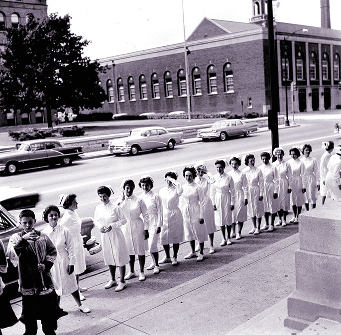 In 1881, four Daughters of Charity arrived in Indianapolis at the invitation of Bishop Francis S. Chatard to open a Catholic hospital. They first operated an infirmary that was located on Vermont Street, and then moved to several different locations before building St. Vincent Hospital on West 86th Street in 1974. This photo shows student nurses from the former St. Vincent School of Nursting processing into SS. Peter and Paul Cathedral in Indianapolis for their graduation ceremony, sometime in the 1950s or 1960s.