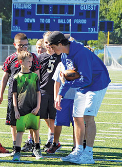 Sports camps are among the ways that Catholic high schools in the archdiocese try to make a continuing connection with students from nearby parish schools. Here, Josh Coons, a student-athlete of Bishop Chatard High School in Indianapolis, shares a tip during a football camp for third- to eighth­graders at the school in the summer of 2017. (Submitted photo)