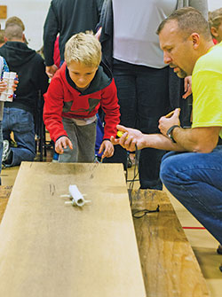 Maddox Novotney launches his improvised “car” while Matt Maddox marks its speed with a timer during the second annual Family STEM Night on Nov. 16, 2017, at St. Barnabas School in Indianapolis. (Submitted photo)
