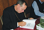 Archbishop Buechlein signing a book
