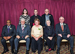 An archdiocesan celebration of Catholic education on Feb. 22 honored three individuals and a parish group whose Catholic values mark their lives. Sitting, from left, are honorees Ody Oruche, Dan and Jan Megel, keynote speaker St. Joseph Sister Carol Cimino, and Gary Ahlrichs, representing the men’s group of Immaculate Heart of Mary Parish in Indianapolis. Standing from left, are archdiocesan superintendent of schools Gina Fleming, Archbishop Charles C. Thompson, and Father Jeffrey Godecker, who helped found the men’s group of Immaculate Heart of Mary Parish in 2001. (Photo by Rob Banayote)