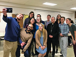 Indiana University students crowd in for a photograph with Archbishop Charles C. Thompson at St. Paul Catholic Center in Bloomington on Feb. 25. This was the archbishop’s first visit to the parish as leader of the archdiocese. (Photo by Katie Rutter)