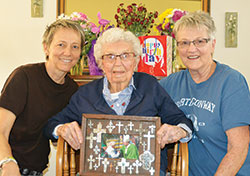 Just days after her 109th birthday, Mary Weir, center, of St. Thomas the Apostle Parish in Fortville, poses in her home with her granddaughter, Paige Hunt, left, and her daughter, Peggy Hunt, who both help care for Weir. The centenarian proudly displays a photo of her meeting then‑Archbishop Joseph W. Tobin in 2016. (Photo by Natalie Hoefer)