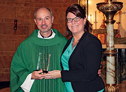 During Catholic Schools Week in January, Gina Fleming, superintendent of Catholic schools in the archdiocese, presents an award to Father Christopher Wadelton, pastor of St. Philip Neri Parish in Indianapolis, honoring him as an archdiocesan nominee for the national “Lead, Learn, Proclaim” Award from the National Catholic Educational Association (NCEA). Since then, Father Wadelton has been chosen for the national honor which recognizes “excellence and distinguished service in Catholic school education.” He will receive the award on April 3 at the NCEA convention in Cincinnati. (Submitted photo)