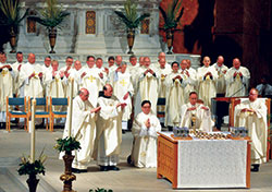 Archbishop Charles C. Thompson prays the eucharistic prayer during the chrism Mass. He is joined at the altar by Msgr. William F. Stumpf, vicar general, left, Conventual Franciscan Father James Kent, provincial of the Our Lady of Consolation Province based in Mount St. Francis, and Father Joseph Newton, vicar judicial, and several concelebrating priests. Deacon Nathan Schallert, third from left, kneels in prayer. (Photos by Sean Gallagher)