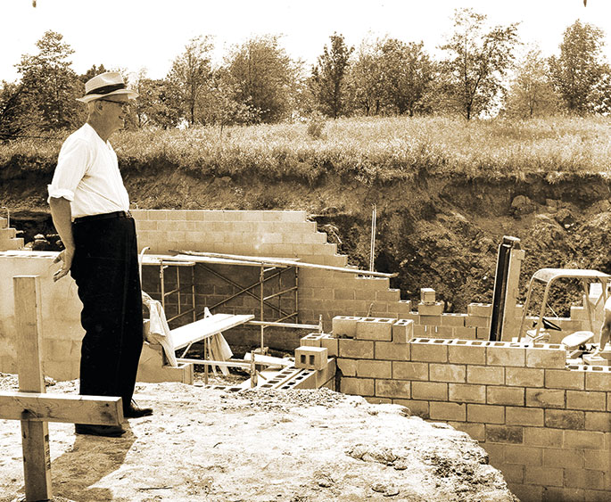 In this 1966 photo, Father Meinrad Rouck, pastor of St. Mary Parish in Mitchell and dean of the former Bedford Deanery, surveys the construction of St. Mary’s new church building. According to the June 17, 1966, issue of The Criterion, construction of the new church building was delayed for several months when deposits of limestone were discovered underneath the building site. St. Mary Parish, which was founded in 1869, celebrated the dedication of their new church with Archbishop Paul C. Schulte on May 21, 1967.