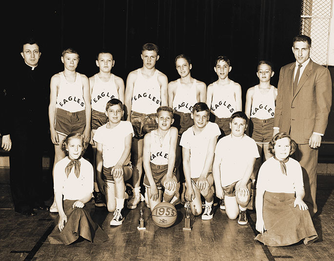 Shown here are the 1955 Eagles basketball team and cheerleaders from the former St. John the Evangelist Parish in Enochsburg. The priest at left is Father Ambrose Schneider, longtime pastor of the Batesville Deanery faith community. According to a note on the back of the photo, the team won the Franklin County tournament that year. The former St. John the Evangelist Parish merged with the former St. Maurice Parish in Decatur County in 2014. St. Catherine of Siena Parish in Decatur County was then formed from the two previous parishes.