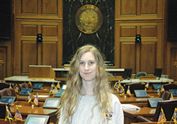 Sixteen-year-old Paige Moore poses in the House of Representatives chambers at the Indiana Statehouse in Indianapolis. The sophomore at Roncalli High School in Indianapolis successfully lobbied earlier this year for a new law that will benefit her and other students at private high schools in Indiana. (Photo by John Shaughnessy)