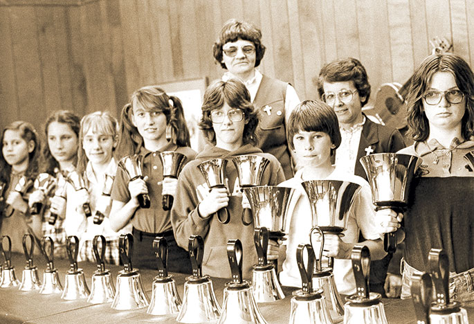 In this photo, the fourth-, fifth- and sixth-grade bell choir of St. Charles Borromeo Parish in Bloomington poses for a group photo in May 1981. Standing behind them are Providence Sister Mary Moller (back row left), who served as principal of the parish’s school, and Providence Sister Regina Marie McIntyre (back row right), who was the parish music director. According to The Criterion article accompanying the original photo, between 85 and 90 children were involved in hand bell choirs at St. Charles Borromeo Parish in 1981.