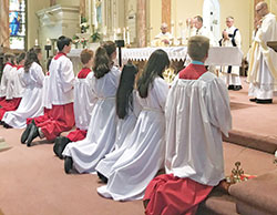 Altar servers kneel in prayer while Archbishop Charles C. Thompson prays the eucharistic prayer during a June 3 Mass at St. Joseph Church in Shelbyville to celebrate the 150th anniversary of the Batesville Deanery faith community’s founding. (Submitted photo by Amy Johnson)