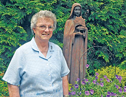 Franciscan Sister Christa Franzer poses beside a statue of St. Clare of Assisi on the grounds of the Oldenburg motherhouse of her community, the Congregation of the Sisters of the Third Order of St. Francis. On April 15, she was elected the superior, known as congregational minister, of the community and will serve in that role for a six-year term. (Photo by Sean Gallagher)