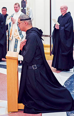 Benedictine Brother Lorenzo Penalosa kneels during a ritual after professing solemn vows on Aug. 15 as a monk of Saint Meinrad Archabbey in St. Meinrad. His hair has been cut in what is traditionally called a corona (Latin for “crown”). Among other things, it is a symbol of the humility at the heart of monastic life. (Photo courtesy of Saint Meinrad Archabbey)