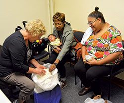 Birthline volunteer Barbara Lemen, left, China Jones, middle, and Janeane Jones admire a hand-crocheted blanket for China’s 6-week-old son at the Archbishop Edward T. O’Meara Catholic Center in Indianapolis on Oct. 10. (Photo by Natalie Hoefer)