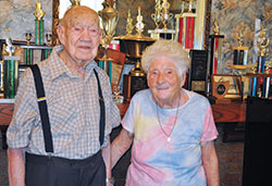 Harold and Helen Klosterkemper stand in their home in Greensburg before all the trophies Harold has won for playing the fiddle.The Klosterkempers are members of St. Mary Parish in Greensburg. (Submitted photo by Jennifer Lindberg)