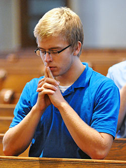 Seminarian Charlie Wessel, a member of St. Simon the Apostle Parish in Indianapolis, kneels in prayer on Aug. 11, 2015, in St. Mary Church in New Albany during a pilgrimage taken during the annual archdiocesan seminarian convocation. Human formation programs at seminaries in the archdiocese help prepare men for the challenges of priestly life and ministry today. (File photo by Sean Gallagher)