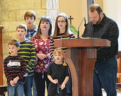 The Chamblee family, members of Holy Name of Jesus Parish in Beech Grove, lead a decade of the rosary during the archdiocesan Morning with Mary event at St. Mary-of-the-Knobs Church in Floyd County on Oct. 13. They are Joseph, left, John Paul, Gabriel, Theresa, Elizabeth (front), Sophia and Jonathan. Not shown but standing behind Jonathan is their daughter Emma. (Photo by Natalie Hoefer)