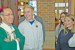 Archbishop Charles C. Thompson shares a light-hearted moment with seniors A.J. Strange, left, Sarah Mattingly and Audrey Troxell of Roncalli High School in Indianapolis. The archbishop met and talked with seniors from 10 Catholic high schools across the archdiocese following the annual Mass he celebrated for them on Nov. 28 at St. Malachy Church in Brownsburg. (Photo by John Shaughnessy)