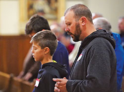 Robbie Falcone, right, and his sons Elijah and Jonah (partially obscured) of St. Elizabeth Ann Seton Parish in Richmond, attend Mass at St. John the Evangelist Church in Indianapolis during the Indiana Catholic Men’s Conference on Nov. 10. (Photo by Katie Rutter)