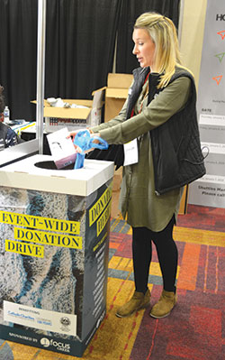 Schyler Smith places items in a donation bin on Jan. 6 during the Fellowship of Catholic University Students SEEK2019 conference held at the Indiana Convention Center in Indianapolis. This was the first year a donation drive was held during the biannual conference. (Photo by Natalie Hoefer)