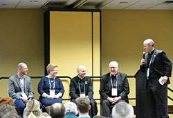 Father John Hollowell, third from left, smiles as he is introduced at a Campus Ministry Track panel discussion on Jan. 6 during SEEK2019 at the Indiana Convention Center in Indianapolis. (Photo by Natalie Hoefer)