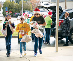 St. Elizabeth Ann Seton students Gwynie Falcone, left, Jackie Clemente, Addi Guiley and Allison Hamilton deliver fruit baskets to senior citizens at a nearby apartment complex in Richmond before Christmas. (Submitted photo)