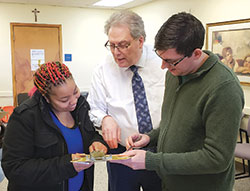 During a visit to the archdiocese’s Crisis Office in Indianapolis, Takecia Keys, left, gets help filling out a food selection form from David Bethuram, center, executive director of Catholic Charities in the archdiocese, and Zach Sperka, assistant director of the Crisis Office. (Submitted photo)