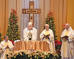 Archbishop Charles C. Thompson elevates the Eucharist during a Mass on Jan. 13 to celebrate the 50th anniversary of the founding of St. Paul Catholic Center in Bloomington. Around the altar are clergy from the parish, from left, Deacon Ron Reimer, Dominican Father Justice Pokrzewinski and Dominican Father John Meany. (Photo by Katie Rutter)