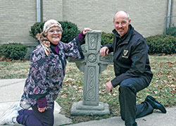 Linda Clodfelter and Father Christopher Wadelton are all smiles as they pose for a photo near a Celtic cross on the grounds of the former Holy Cross Parish in Indianapolis. Both are involved in the 29th annual St. Patrick’s Day celebration in the Holy Cross Central School gymnasium on March 10—a celebration that helps feed the homeless, shut-ins and other people in need throughout the year. (Photo by John Shaughnessy)