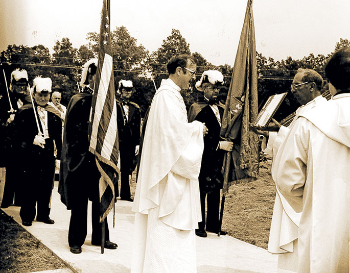 This photo shows the Knights of Columbus in procession for the blessing of a new church building at St. Joseph Parish in Crawford County. The previous church was destroyed in the devastating tornadoes of April 3, 1974. The new church was dedicated on Aug. 27, 1978. Reading a prayer is Father (later Msgr.) Francis Tuohy, who was vicar general of the archdiocese at that time. Holding the book is Father Andrew Diezeman, who was the pastor of the New Albany Deanery parish.