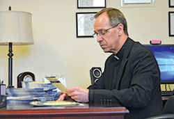 Archbishop Charles C. Thompson reads one of more than 1,000 prayer intentions stacked on his desk that have been sent in so far with this year’s United Catholic Appeal pledge intentions and payments. He reads and prays for the intentions each year. Usually there are less than 100 requests. (Photo by Natalie Hoefer)