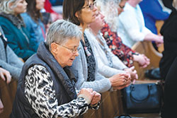 Left, Harla Lyle, a member of St. Susanna Parish in Plainfield, prays during Mass in St. John the Evangelist Church in Indianapolis during the Indiana Catholic Women’s Conference on March 23. (Photo by Katie Rutter)