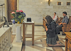 Theresa Inoue, coordinator of evangelization and missionary discipleship at SS. Peter and Paul Cathedral Parish in Indianapolis, kneels in prayer on May 8 before the cremated remains of William “Paco” Pryor before a funeral for him in the cathedral’s Blessed Sacrament Chapel. Pryor had lived as a homeless person for more than 20 years behind the cathedral and died on April 3 in a nursing home in Indianapolis. (Photo by Sean Gallagher)