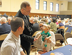 Archbishop Charles C. Thompson meets 9-month-old Miriam Babb and her parents, Rory and Diana Babb, at the third annual Circle of Giving dinner held on May 9 at the Archbishop Edward T. O’Meara Catholic Center in Indianapolis. The Babbs, who are members of St. John the Evangelist Parish in Indianapolis, were among those recognized for their generous contributions to the Archdiocese of Indianapolis and its ministries. (Photo by Victoria Arthur)
