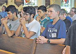 Jose Trinidad, left, Jose Ortiz and Brandon Todd kneel in prayer on June 26 during a Mass at St. Francis Xavier Basilica in Vincennes. The three were among 39 high school participants in Bishop Bruté Days, an annual archdiocesan vocations camp. Trinidad and Ortiz are members of St. Bartholomew Parish in Columbus. Todd is a member of St. Patrick Parish in Terre Haute. (Photo by Sean Gallagher)