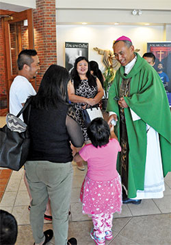 Bishop Lucius Hre Kung of the Hakha Diocese in Myanmar (formerly Burma) greets a young girl and other Burmese refugees after celebrating Mass in the Hakha Chin language on Aug. 4 at St. Barnabas Church in Indianapolis, the faith home of refugees from the Hakha region of Myanmar. (Photo by Natalie Hoefer)