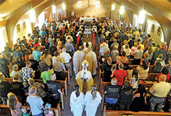 Archbishop Charles C. Thompson processes on June 24, 2018, into a filled St. Isidore the Farmer Church in Perry County to celebrate a Mass to mark the 50th anniversary of the founding of the Tell City Deanery faith community. Father Anthony Hollowell, administrator of St. Mark Parish in Perry County and St. Paul Parish in Tell City, says regularly attending Sunday Mass is a critical part of the formation of the conscience of Catholics. (File photo by Sean Gallagher)