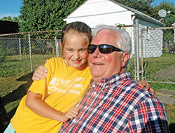 Greg Mark shares a smile with his granddaughter Bridget Mayer as he sits on the sidelines before a kickball game on the playground of St. Therese of the Infant Jesus (Little Flower) School in Indianapolis. (Photo by John Shaughnessy)
