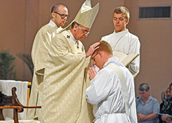 Archbishop Charles C. Thompson ritually lays hands on then-transitional Deacon Jeffrey Dufresne during a June 2, 2018, priestly ordination Mass in SS. Peter and Paul Cathedral in Indianapolis. Assisting at the liturgy are then-transitional Deacon Timothy DeCrane, left, and seminarian Charlie Wessel. Archbishop Thompson has announced a restructuring of the archdiocesan vocations office. (File photo by Sean Gallagher)