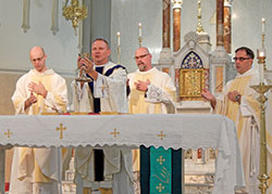 Father Rick Nagel elevates the Eucharist in St. John the Evangelist Church in Indianapolis during a Mass celebrated for those attending the annual Indiana Catholic Men’s Conference on Oct. 5. Concelebrants include Father Michael Keucher, left, Father Michael Lightner and Congregation of Marians of the Immaculate Conception Father Donald Calloway. Approximately 375 men attended the conference. (Photo by Mike Krokos)