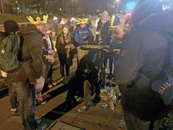 After the closing Mass for the National Catholic Youth Conference on Nov. 23 in Indianapolis, young people on the way to their hotel stopped to offer water and snacks to a homeless man. They then prayed over him, led by the young man on the far left. (Photo by Natalie Hoefer)
