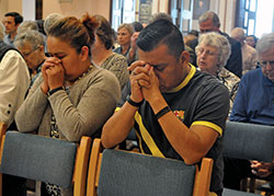 Mercedez Vincens, left, and Domingo Lopez, both members of St. Monica Parish in Indianapolis, kneel in prayer with other Catholics from throughout central and southern Indiana during the April 16, 2019, chrism Mass at SS. Peter and Paul Cathedral in Indianapolis. (Photo by Sean Gallagher)
