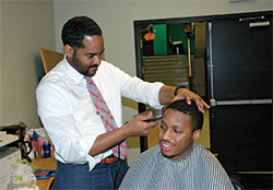 Even in his role as interim president of Providence Cristo Rey High School in Indianapolis, Fred Yeakey finds time to give free haircuts to students, including senior Richard Underwood. Yeakey uses the haircuts as part of his plan of “grooming the outer man while guiding the inner man.” (Photo by John Shaughnessy)