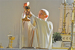 Father John Hollowell elevates the Eucharist during a July 31, 2013, Mass at Annunciation Church in Brazil. Recently diagnosed with a brain tumor, Father Hollowell has offered up his sufferings on behalf of victims of clergy sexual abuse. He is the pastor of Annunciation Parish in Brazil and St. Paul the Apostle Parish in Greencastle, and Catholic chaplain of DePauw University, also in Greencastle. (File photo by Sean Gallagher)