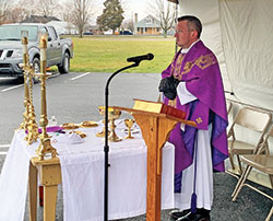 Father Shaun Whittington celebrates Mass on March 15 under a tent in the parking lot of St. Anthony Parish in Morris. The Mass was broadcast over a low-power FM transmitter to parishioners joining him in prayer in their cars. The pastor of St. Anthony Parish as well as St. Nicholas Parish in Ripley County, Father Whittington offered parking lot Masses in his faith communities to make the Eucharist available to his parishioners in a way that would prevent the spread of the coronavirus. (Submitted photo)
